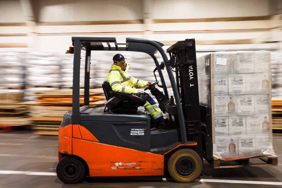 Person on a forklift manovering goods around a warehouse.