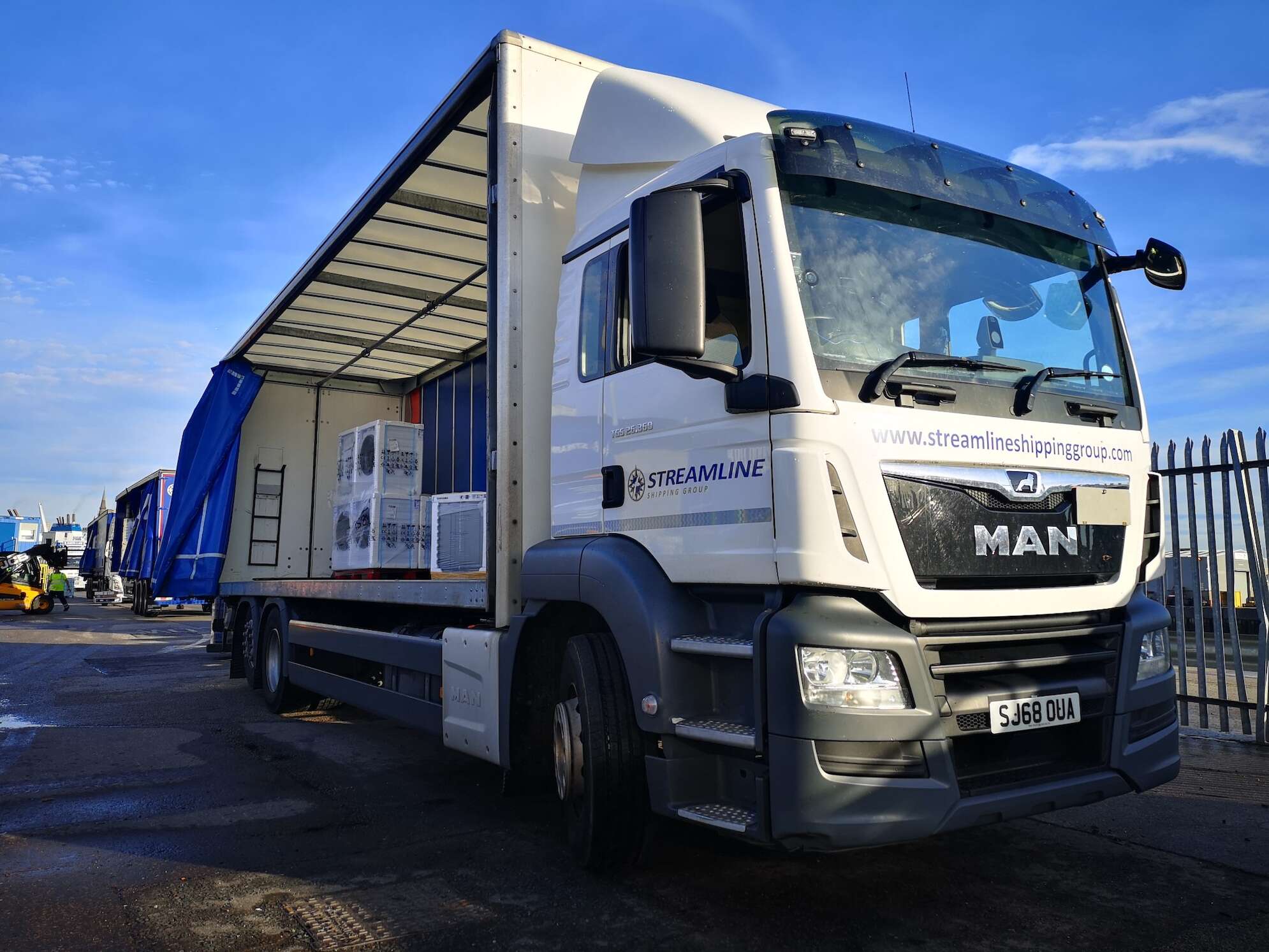 Streamline shipping lorry parked up in a depot wit side door open, waiting for goods to be removed.