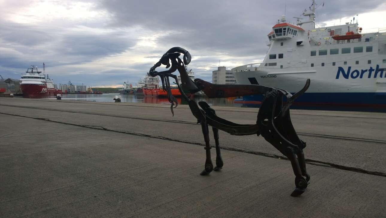 A large steel model animal standing outdoors next to a harbour