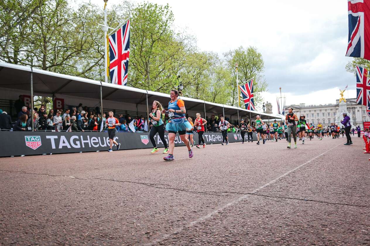 Runners photographed mid-race with spectators, UK flags and Buckingham Palace in the background